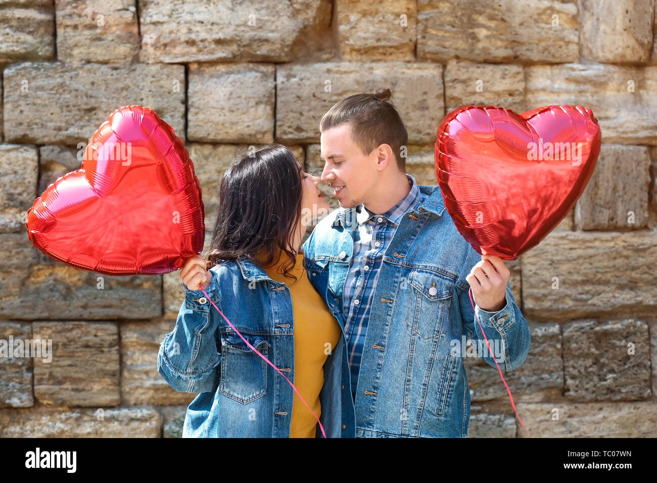 Glückliches junges Paar mit herzförmigen Luftballons im Freien Stockfoto