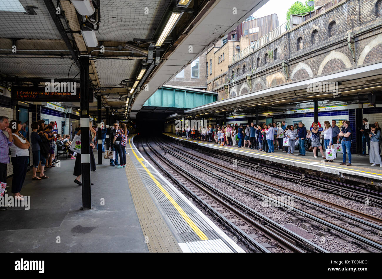 Die Menschen warten auf den Plattformen am Sloane Square London Underground Station für einen Zug zu gelangen. Stockfoto