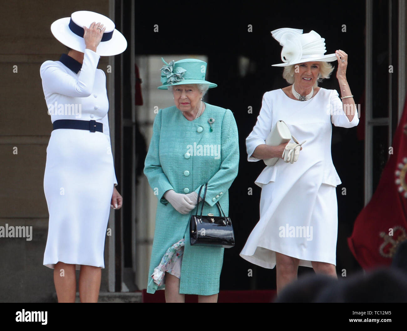 Melania Trump (links) und die Herzogin von Cornwall halten an ihren Hüten, da sie neben Königin Elizabeth II. während der Feierlichen Willkommen im Buckingham Palace, London stehen, am ersten Tag seiner dreitägigen Staatsbesuch in Großbritannien. Stockfoto