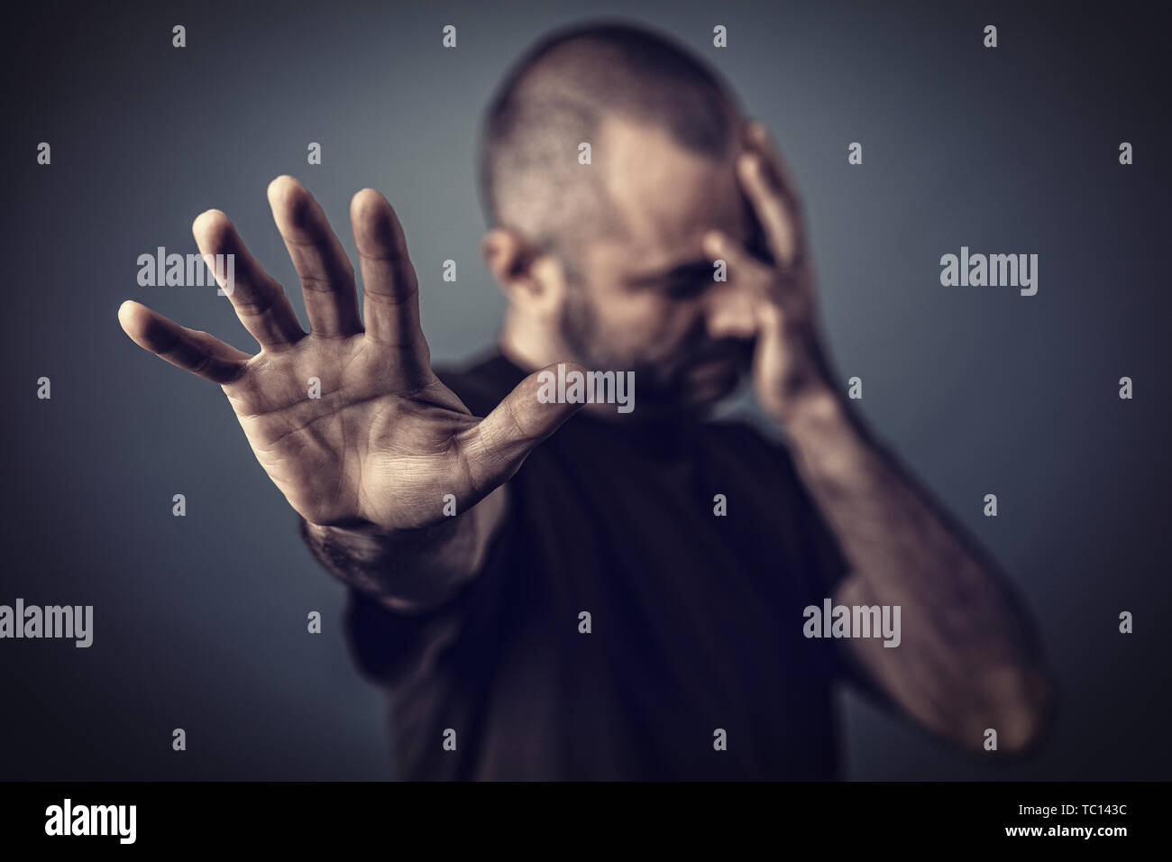 Verzweifelten Mann mit der Hand über sein Gesicht und eine andere Hand nach vorne, um sich zu schützen. Stockfoto