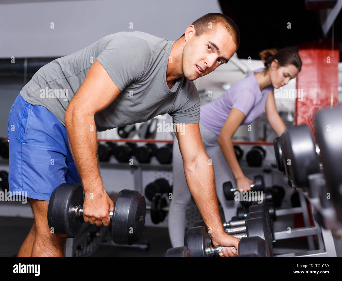 Sportliche Menschen unter schweren Sport Hantel auf dem Regal im Fitnessstudio Stockfoto