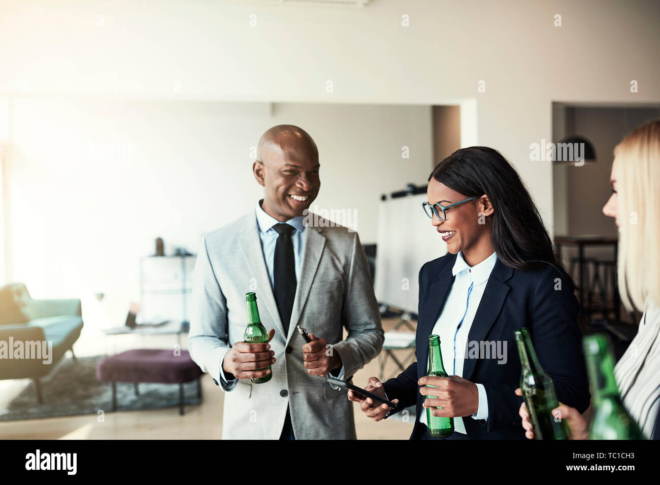 Lächelnden jungen afrikanischen amerikanischen Geschäftsfrau mit einem Mitarbeiter Fotos auf ihrem Mobiltelefon, während sie Getränke in einem Büro nach der Arbeit Stockfoto