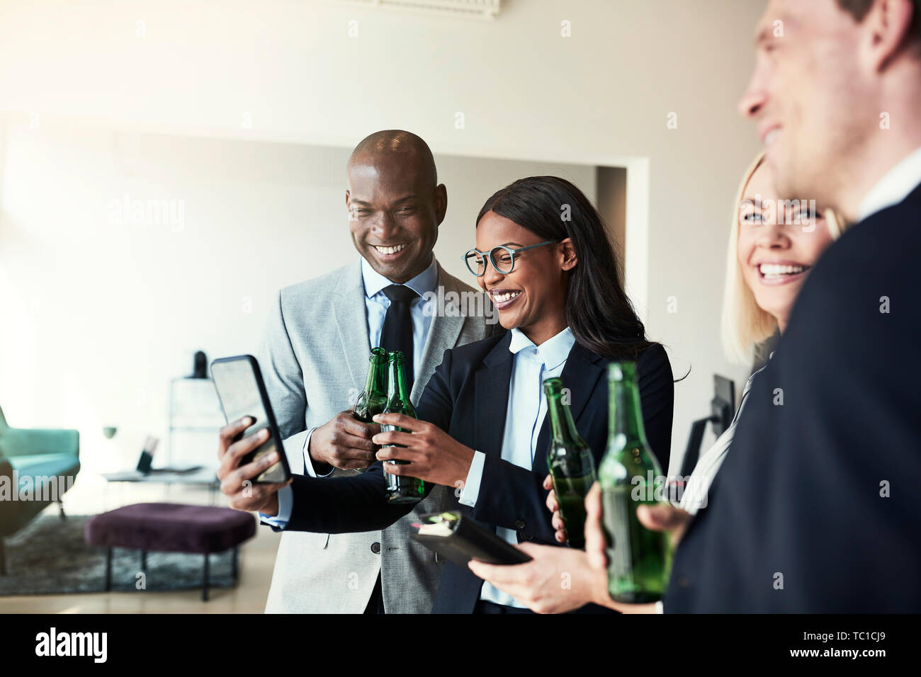 Junge afrikanische amerikanische Geschäftsfrau, lächeln Mitarbeiter Fotos auf ihrem Mobiltelefon, während sie Getränke in einem Büro nach der Arbeit Stockfoto