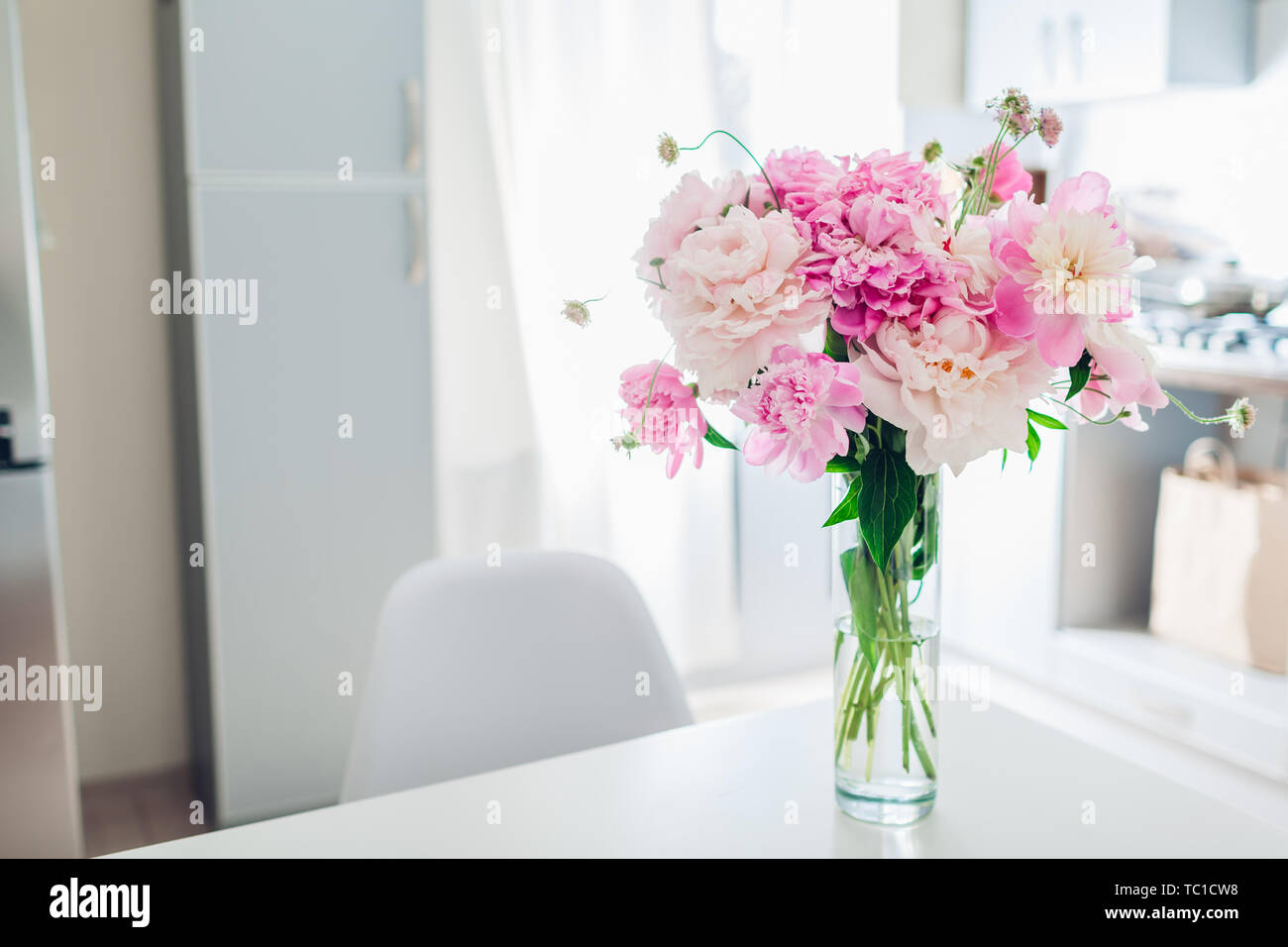 Rosa Pfingstrosen. Moderne Küche Design. Innenraum weiss und silber Küche mit Strauß mit frischen Blumen geschmückt. Stockfoto