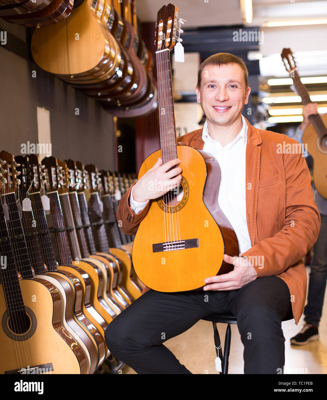 Glücklich Mann im mittleren Alter die beste akustische Gitarre in der musikalischen Shop Stockfoto