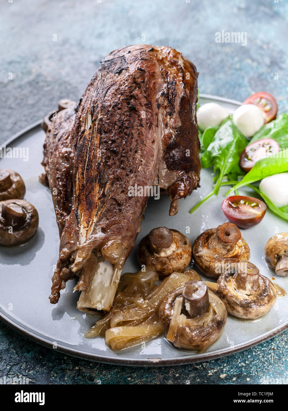 Close-up gebratenes Lamm mit Pilzen und Gewürzen und Kräutern auf einer  runden Platte auf einen konkreten Hintergrund. Halal Fleisch und  Lebensmittel Stockfotografie - Alamy