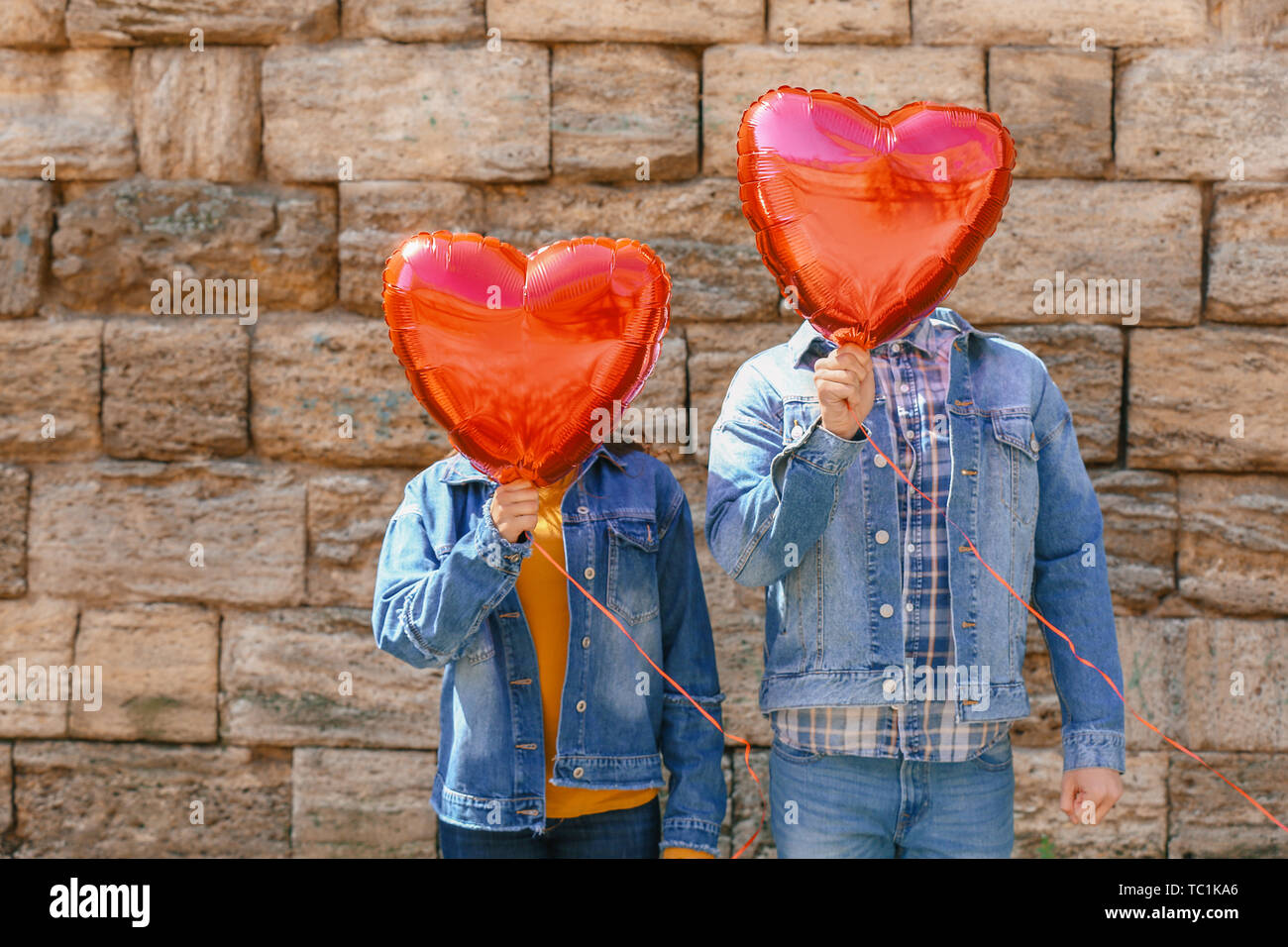 Glückliches junges Paar mit herzförmigen Luftballons im Freien Stockfoto