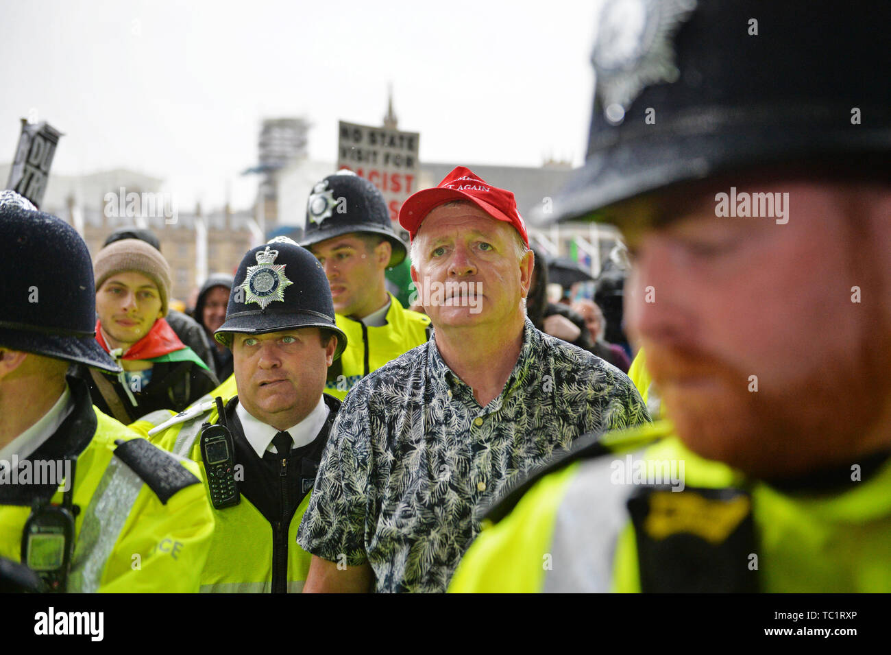 Ein Trumpf Unterstützer wird von der Polizei nach milchshake am Parliament Square, London Am zweiten Tag des Staatsbesuchs in Großbritannien durch US-Präsident Donald Trump abgedeckt begleitet. Stockfoto