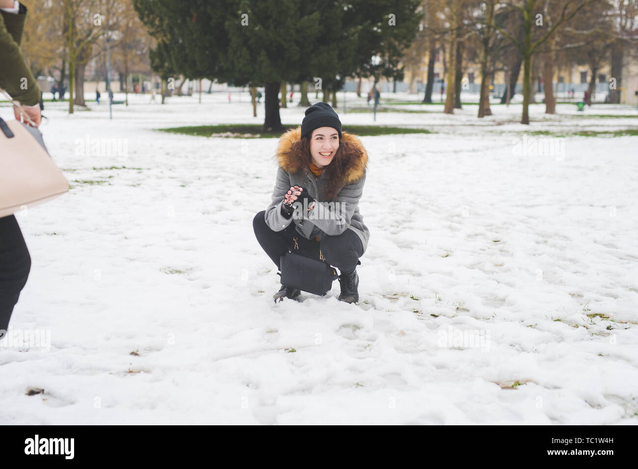 Porträt der jungen Frau in die Hocke, im Park mit Schnee - Unbekümmertheit, Urlaub, neue Generation Stockfoto