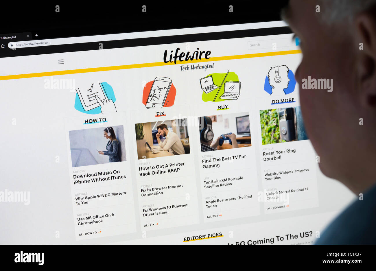 Mann, der an einem Computer Monitor Surfen durch das Internet auf der Lifewire Website im World Wide Web mit einem Internet Browser suchen. Stockfoto