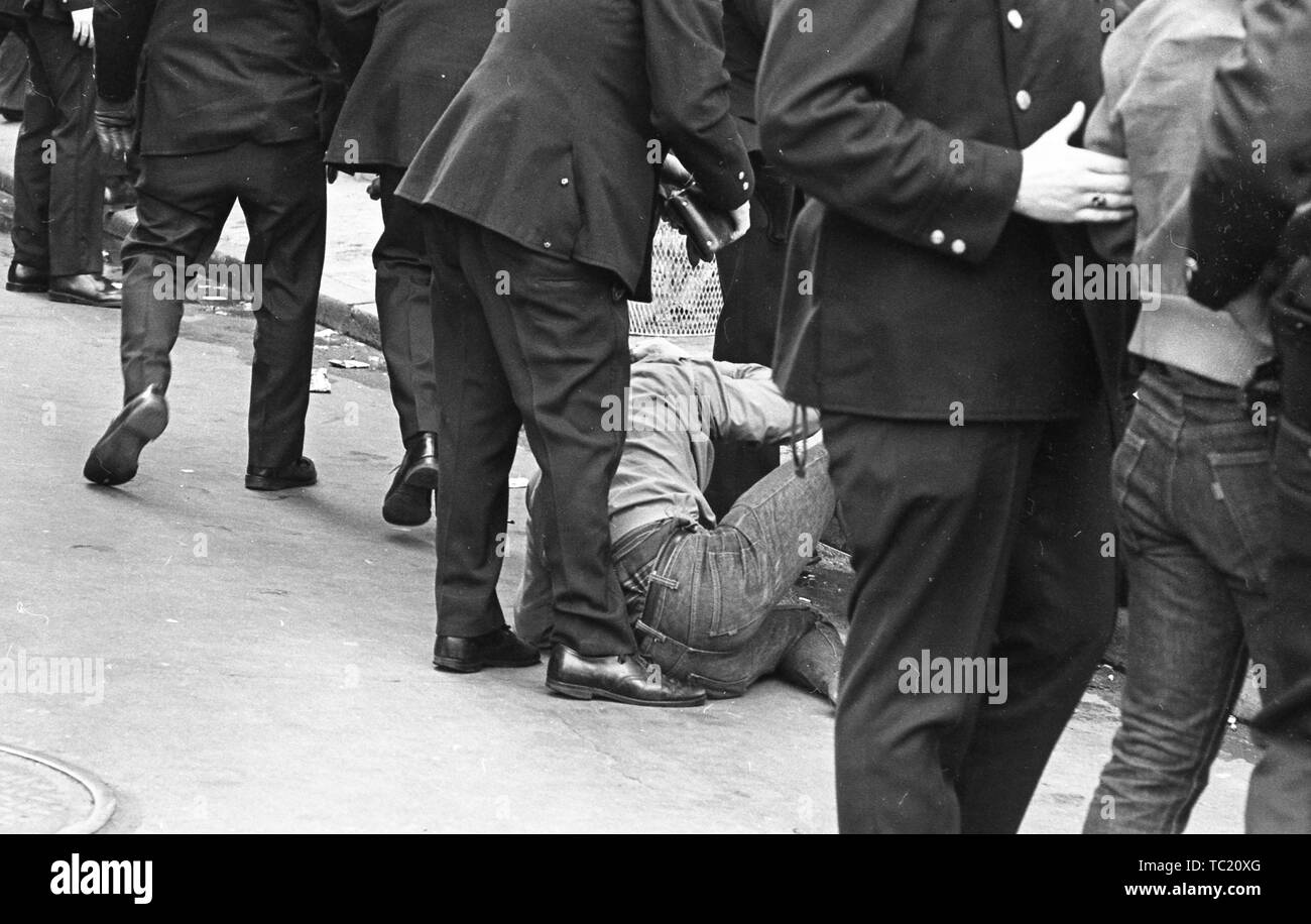 Zivilisten in Jeans, eine auf dem Boden in der Nähe der Bordsteinkante eingerollt, werden durch uniformierte Beamte gedämpft, sichtbar von der Rückseite, während das Haus mit Ehre Parade, New York City, New York, 31. März 1973. () Stockfoto