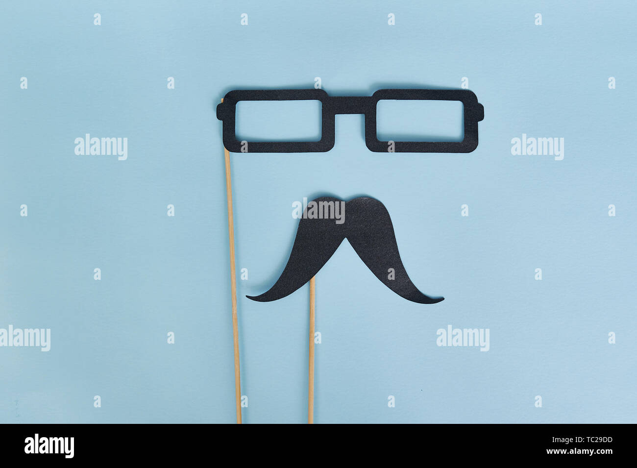 Dekorativer Mann Schnurrbart und schwarze Brille auf hellblauem Papierhintergrund. Draufsicht für Grußkarte mit Platz für Text. Glücklicher Vatertag flach Stockfoto