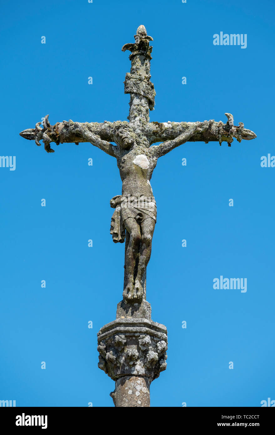 Stein Statue von Christus am Kreuz vor blauem Himmel auf einem Friedhof in La Feuillée, Bretagne, Frankreich. Stockfoto