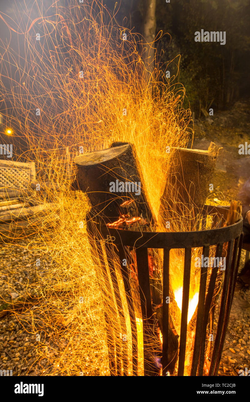 Brennende Feuergrube Stahlkorb in Dunkelheit auf kalten Oktober Nacht im Herbst mit Feuer Funken um schwimmende Stockfoto