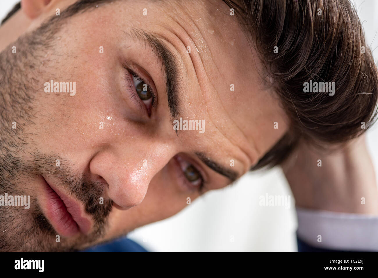Portrait von erschöpft stattlicher Mann mit Verschwitzten Gesicht leiden von Hitze auf Weiß Stockfoto