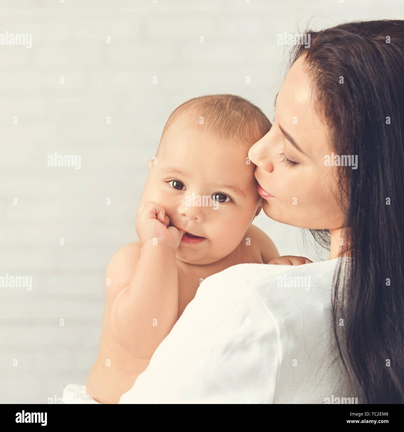 Mutter küssen Kind, Baby ruht auf Mom Schulter Stockfoto