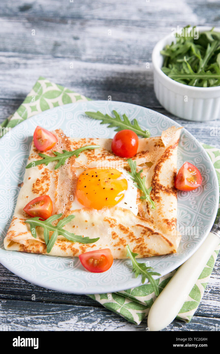 Crepes mit Eiern, Käse, Rucola Blätter und Tomaten. Galette abgeschlossen. Traditionelles Gericht galette Sarrasin Stockfoto