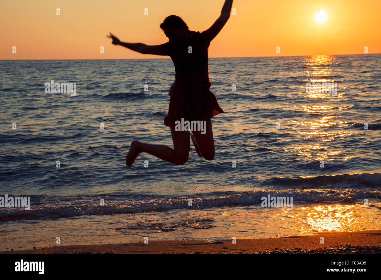 Mädchen springen gegen Sonnenaufgang. Glückliche Frau Relaxen am Strand im Urlaub Korfu Stockfoto