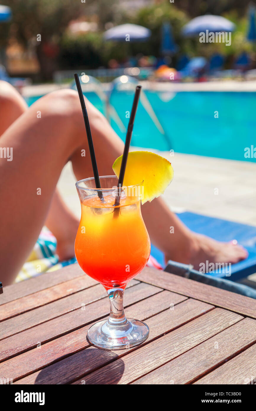 Junge Frau mit Ananas Cocktail kühlen in der tropischen Sonne in der Nähe von Schwimmbad auf einem Liegestuhl Sonnenliege. Mädchen Entspannen und Sonnenbaden im Urlaub Stockfoto