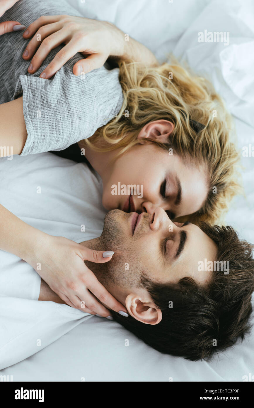 Gerne blonde Frau küssen Freund beim liegen auf dem Bett Stockfoto