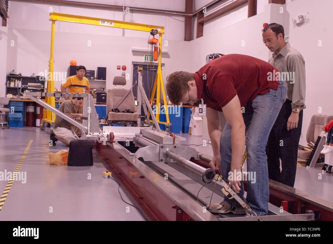 Andreas Merkle betreut Studenten der Ingenieurwissenschaften auf einem Rückhaltesystem in der Biomechanik Test Facility in der Johns Hopkins University Applied Physics Laboratory, 3. Mai 2004. Vom Homewood Sammlung Fotografie. () Stockfoto