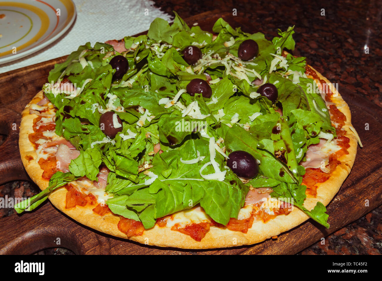 Lecker lecker Pizza mit Käse, Tomaten, Rucola, Oliven, Basilikum auf hölzernen Tisch Stockfoto