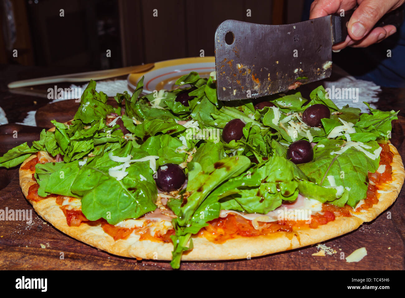 Lecker lecker Pizza mit Käse, Tomaten, Rucola, Oliven, Basilikum auf hölzernen Tisch Stockfoto