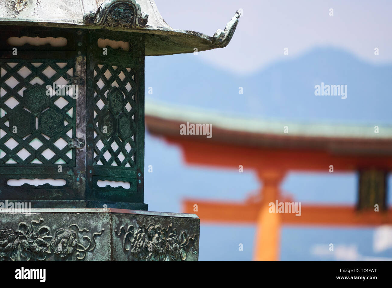 Eine traditionelle Laterne im Vordergrund steht, während die vermilion Torii (Schrein Tor) an der Itsukushima Jinja steigt im Hintergrund. Stockfoto