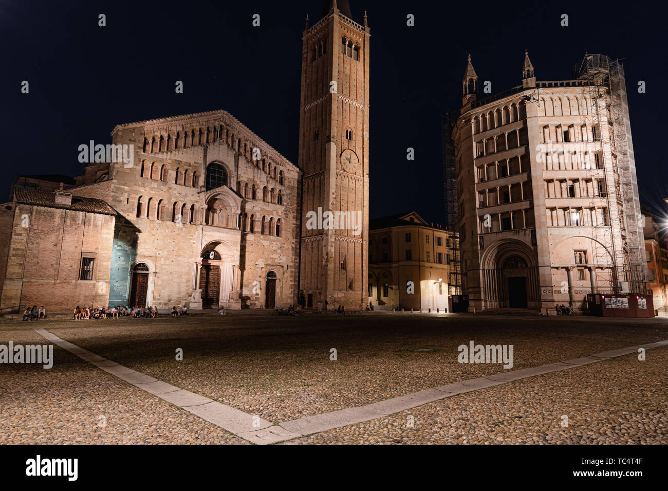 Nachtansicht von Parma, dem Dom und Baptisterium in Piazza Duomo, die von Straßenlaternen beleuchtet Stockfoto