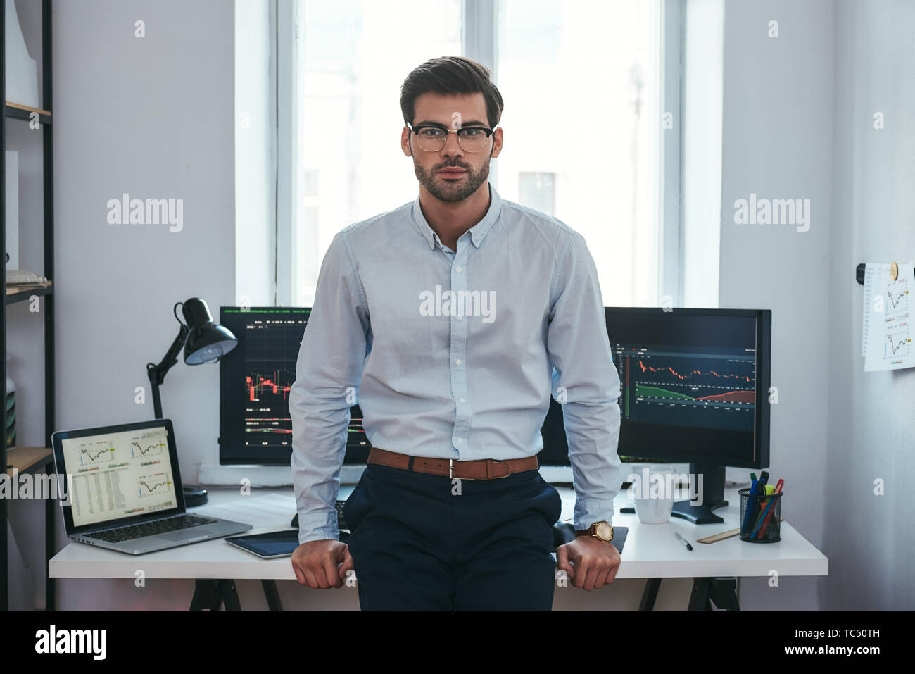 Moderne Händler. Erfolgreiche junge Unternehmer in formelle Kleidung und Brillen an Kamera suchen Im Büro stehen. Börsenmakler. Forex Markt. Handel Konzept Stockfoto