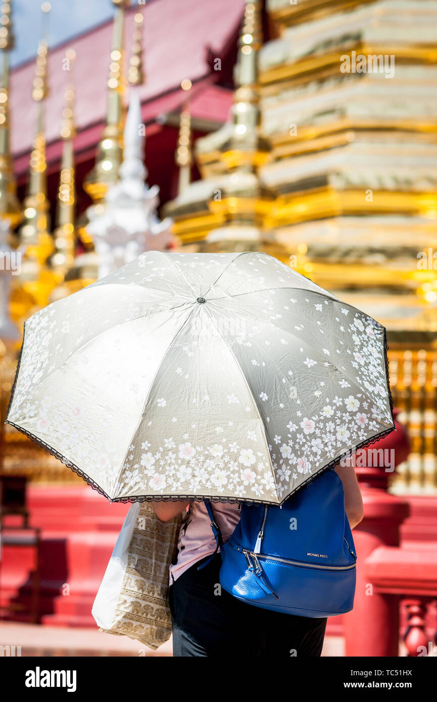 Eine Thailänderin hält einen Regenschirm auf, um sich vor der Sonne im Wat Phra Sing Temple, Chiang Mai, Thailand zu schützen. Stockfoto