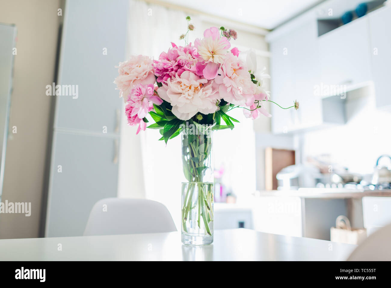 Rosa Pfingstrosen. Moderne Küche Design. Innenraum weiss und silber Küche mit Strauß mit frischen Blumen geschmückt. Stockfoto