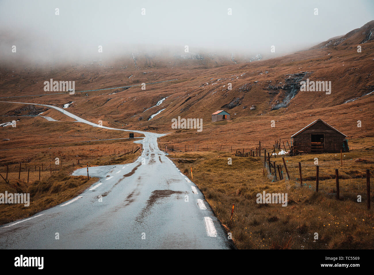 Bild von Reisen auf einer einsamen Straße in den Färöer Inseln. Berge und traditionellen Häusern. Stockfoto
