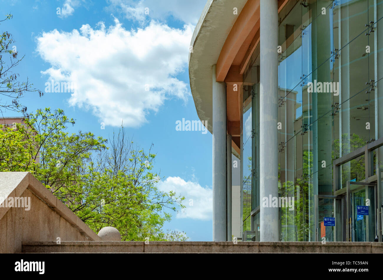 Blauer Himmel, weiße Wolken, grüne Bäume, helles Gebäude im Frühjahr und Sommer. Stockfoto
