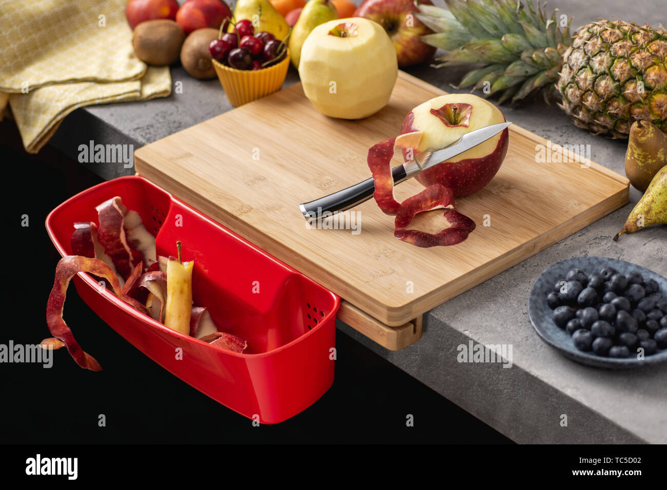 Holz Schneidebrett mit Behälter, Santoku Kochmesser und frisches Obst. Gesunde Ernährung Konzept. Stockfoto