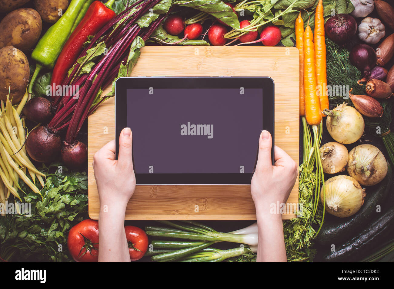 Hände mit Tablet über Frisches Bio-Gemüse Hintergrund. Vegetarische Rezepte. Stockfoto