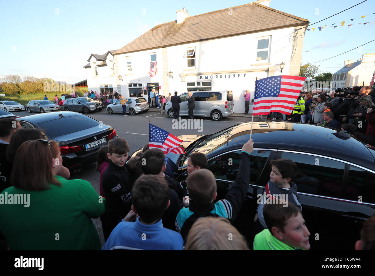 Menschenmassen versammeln um ein Restaurant als Secret Service und bewaffnete Polizisten stehen mit dem Presidential Fahrzeuge im Dorf Doonbeg in der Grafschaft Clare am ersten Tag der US-Präsident Donald Trump Besuch in der Republik Irland. Stockfoto