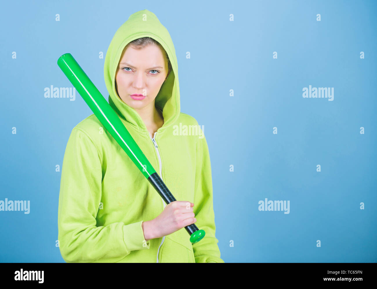 Frau spielen Baseball Spiel oder jemanden zu schlagen. Mädchen Kapuzenjacke halten Baseballschläger blauen Hintergrund. Frau in Baseball Sport. Baseball Spielerin Konzept. Sie ist gefährlich. Mädchen Unruhestifter. Stockfoto