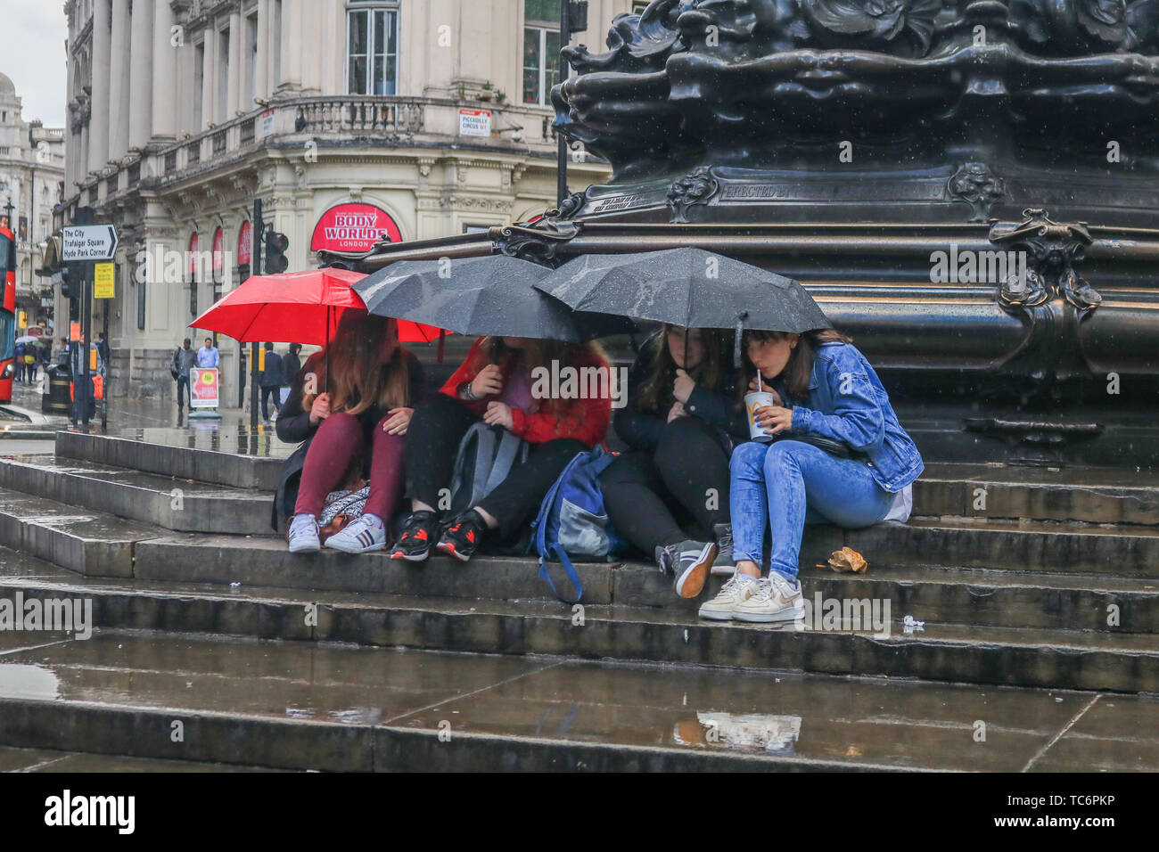 London, Großbritannien. 6. Juni, 2019. Die Menschen drängten sich unter Sonnenschirmen auf den Stufen des Eros Brunnen in Piccadilly Circus aus dem kurze Regenschauer Credit: Amer ghazzal/Alamy leben Nachrichten Stockfoto