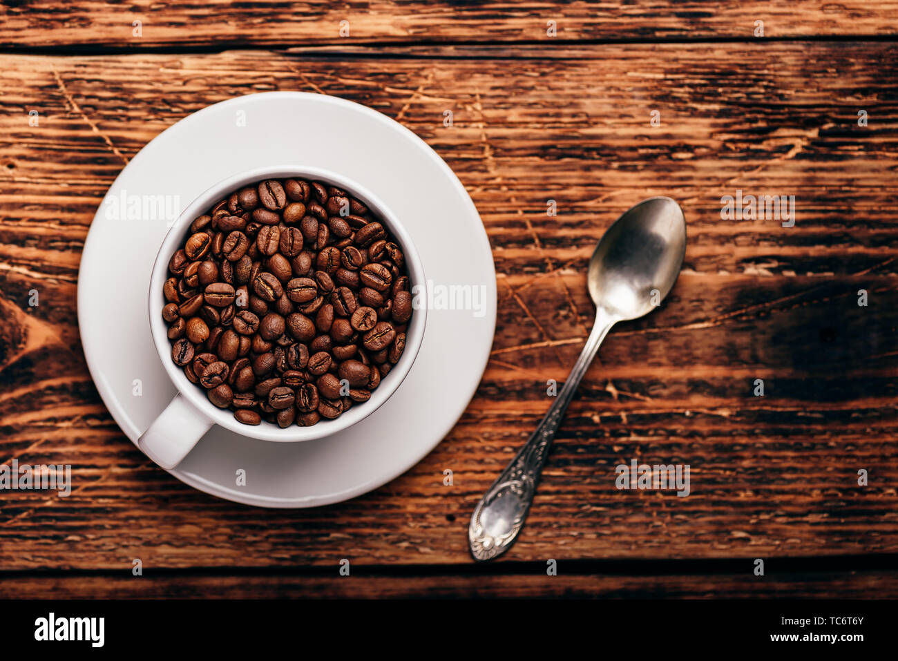 Geröstete Kaffeebohnen in Weiß cup über rustikale Holz- Oberfläche Stockfoto