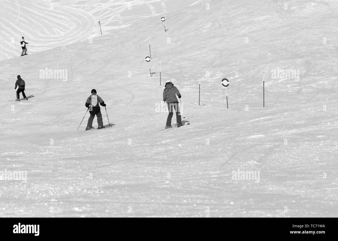 Skifahrer und Snowboarder bergab auf verschneiten Ski am sonnigen Tag verfolgen. Kaukasus Berge im Winter, Georgien, Region Gudauri. Schwarz und Weiß getönten landsca Stockfoto