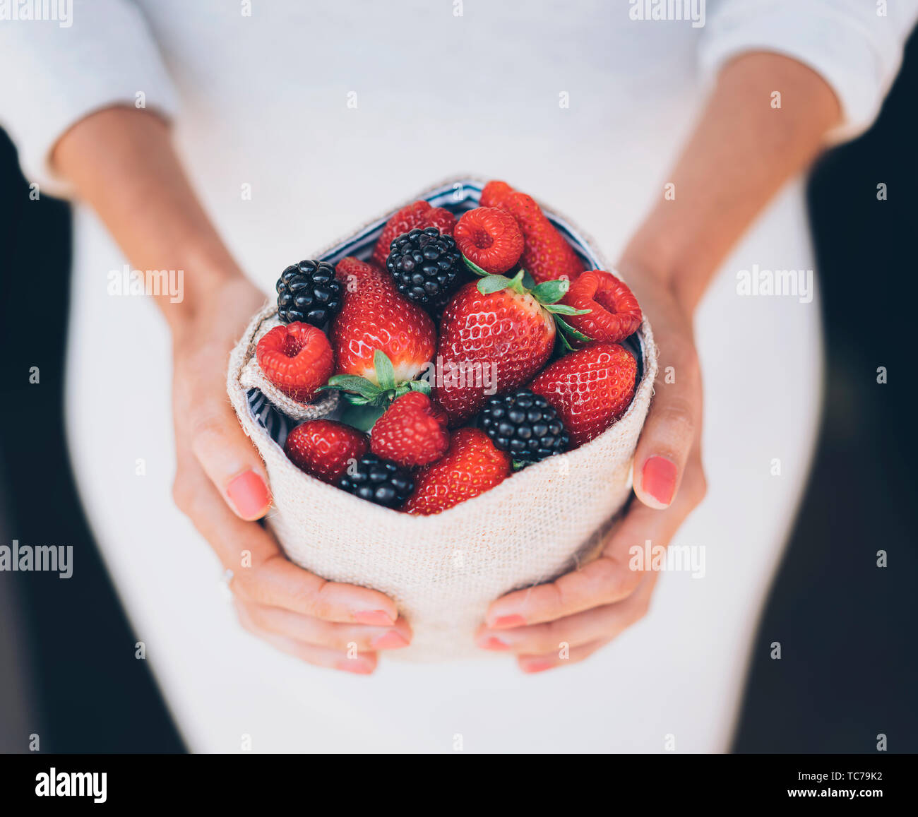 Gesunde und saftige Beeren Früchte in der Frau die Hände mit weißem Kleid Stockfoto