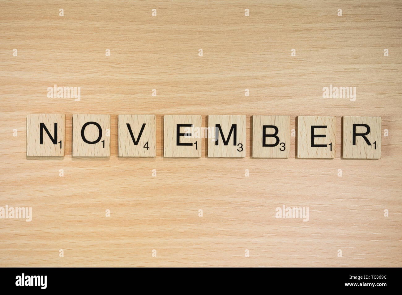 Das Wort November, Dinkel mit Holz Fliesen auf einem Holz Wirkung Hintergrund mit Scrabble nummeriert Punktzahl Werte. Stockfoto