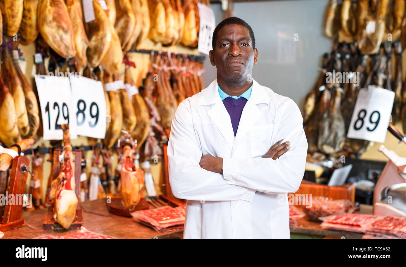 Zuversichtlich Fleisch Delikatessen shop besitzer in der Nähe von Zähler mit traditionellen spanischen Schinken posing Stockfoto