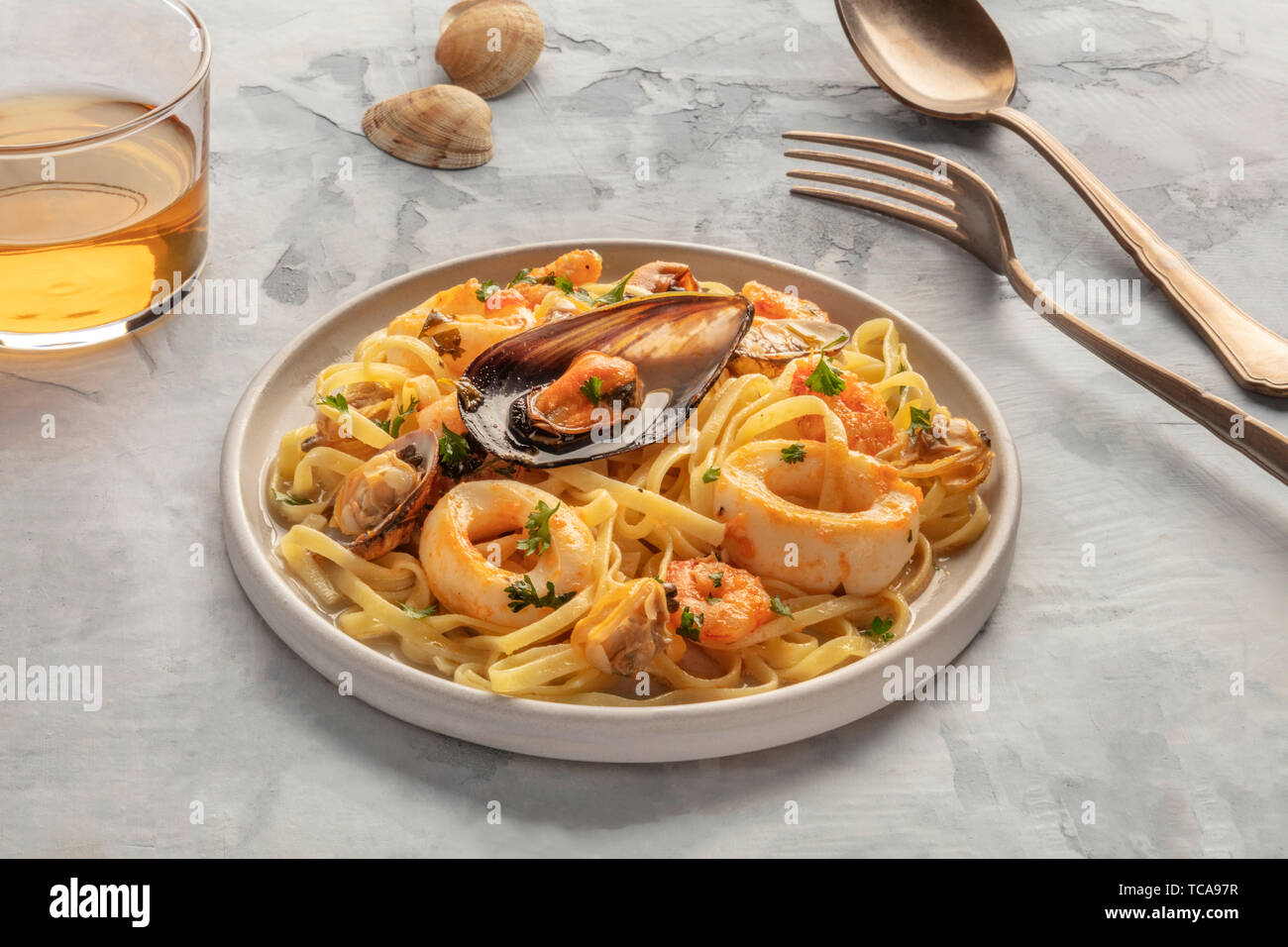 Meeresfrüchte Pasta. Tagliolini mit Muscheln, Garnelen, Muscheln und Tintenfischringe mit einem Glas Weißwein Stockfoto
