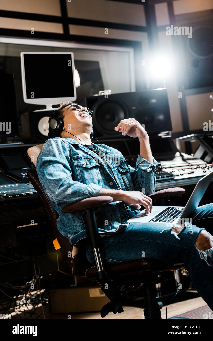 Lächelnd Mixed Race Sound Hersteller in Kopfhörer Musik hören Weiß im Büro Stuhl Stockfoto