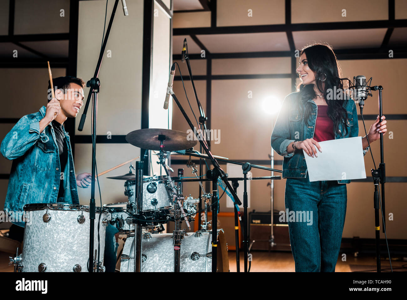 Schönen gemischten Rennen Musiker Schlagzeug und attraktiven Sänger in der Nähe von Mikrofon in Studio Stockfoto