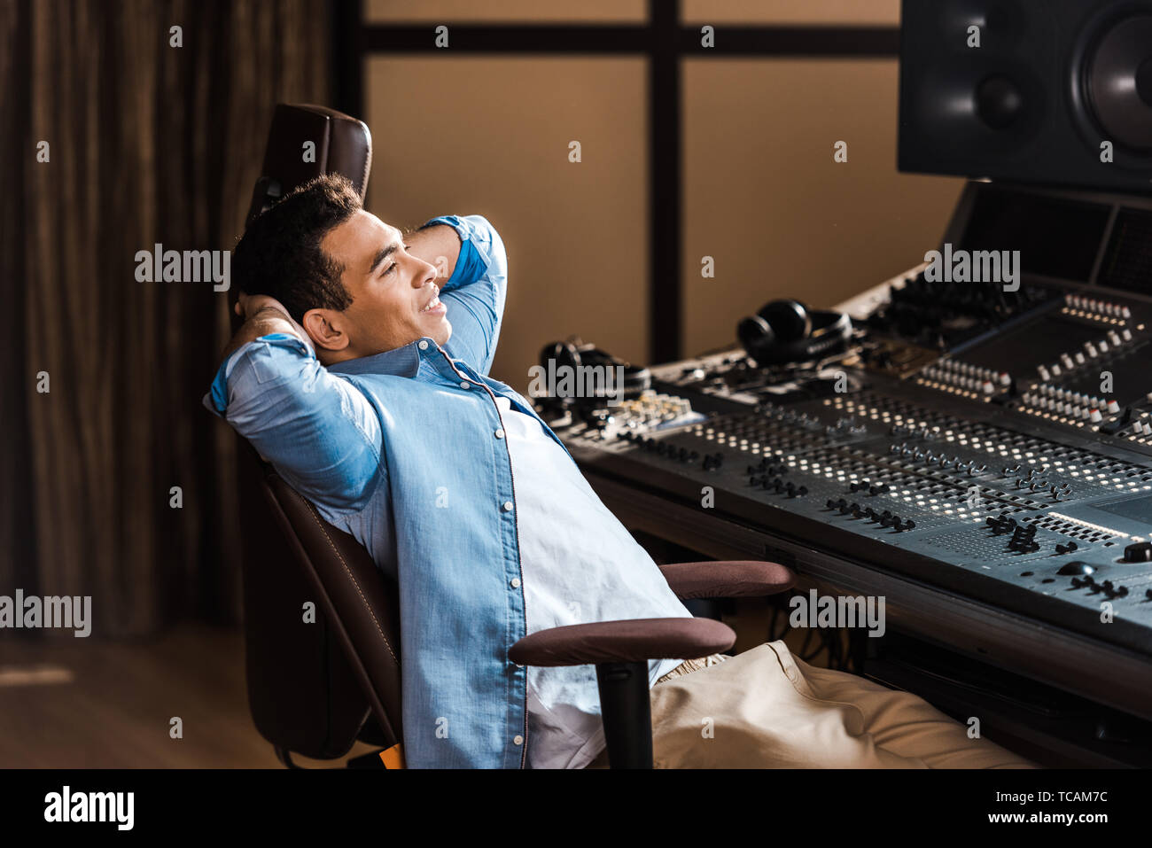 Schöner lächeln Mixed Race Sound Hersteller in Bürostuhl Ausruhen im Recording Studio Stockfoto