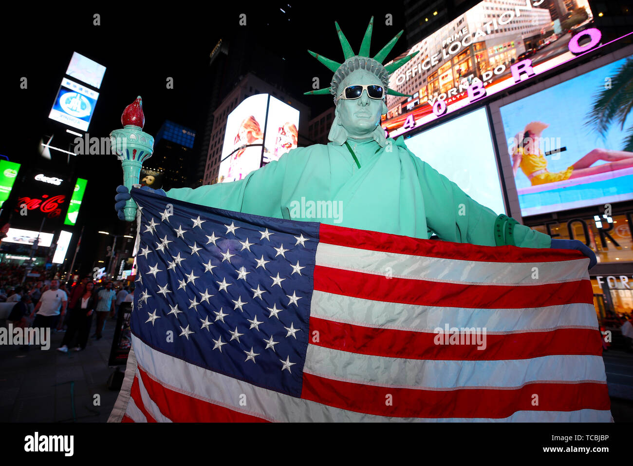 Ein Mann gekleidet wie die Freiheitsstatue halten eine US-Flagge im Times Square, USA Stockfoto