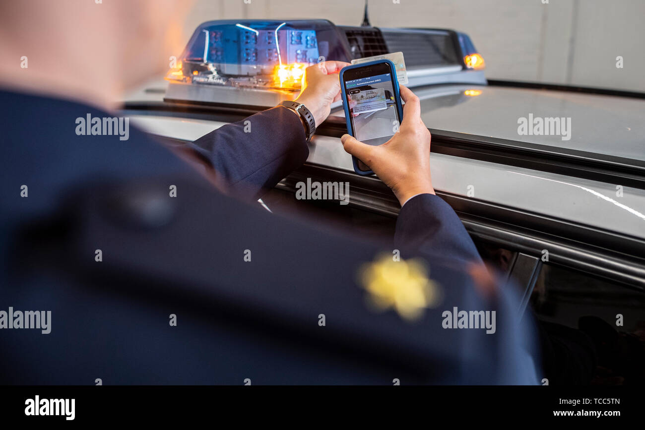 07. Juni 2019, Nordrhein-Westfalen, Dortmund: Ein Polizist durchsucht ein Personalausweis mit einem neuen Smartphone. Mit dieser App können Sie die entsprechenden Daten schnell können während des Betriebs angezeigt. Die Polizei in Nordrhein-Westfalen startet ein Pilotprojekt mit neuen Smartphones und spezielle Apps für die Arbeit der Polizei. Die Geräte werden zunächst von drei Behörden geprüft werden. Das Projekt wird zu einem späteren Zeitpunkt erweitert werden. NRW-Innenminister Reul (CDU) stellt die neuen Geräte und die damit verbundenen Chancen für die Polizei in Nordrhein-Westfalen. Foto: Guido Kirchner/dpa Stockfoto